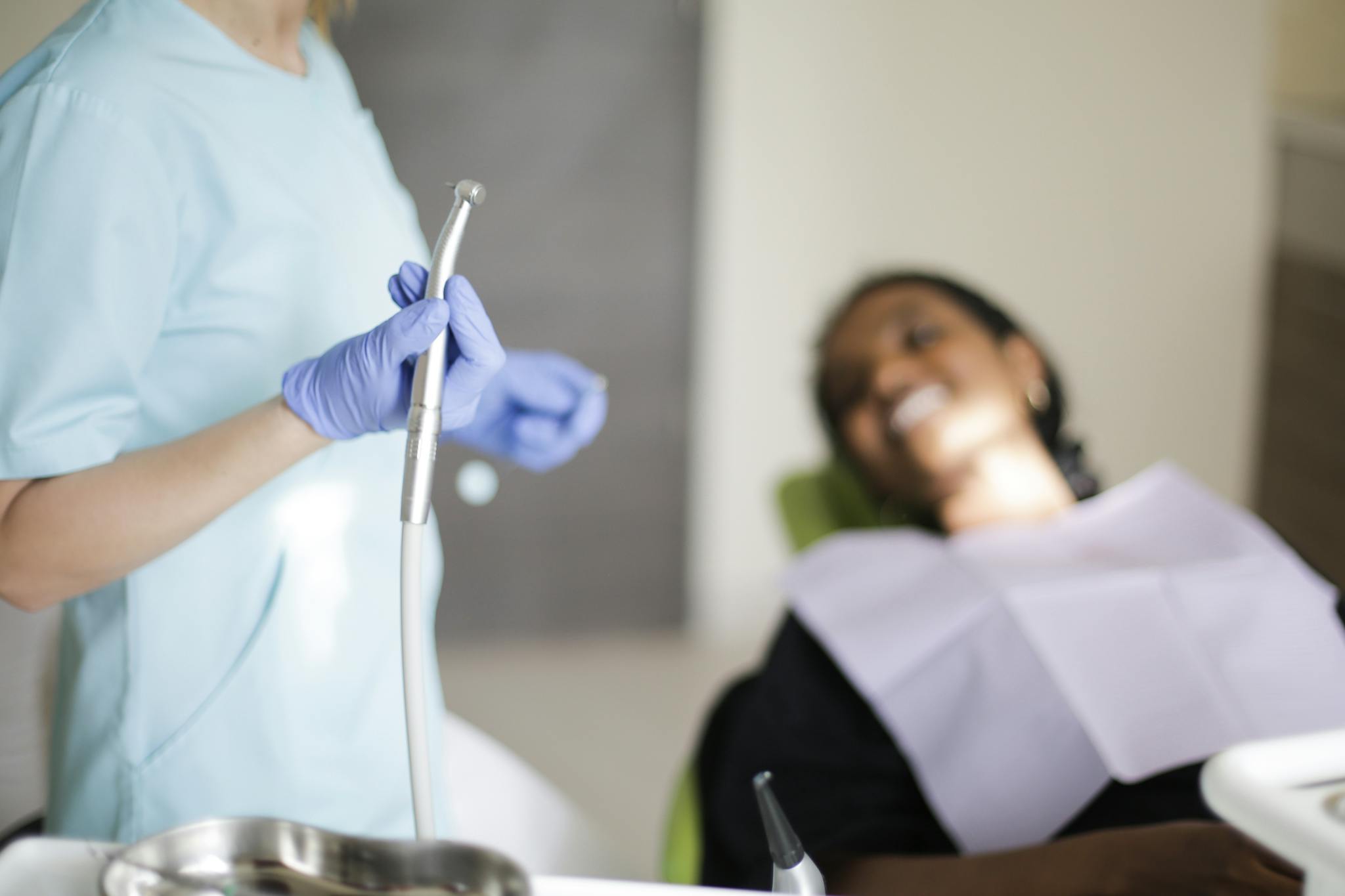 A dentist prepares tools while a patient smiles, showcasing professional dental care.
